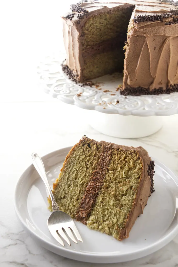 A slice of banana cake with the larger cake in the background.