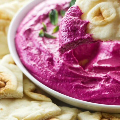 Dipping naan bread into red beet labneh dip recipe for entertaining.