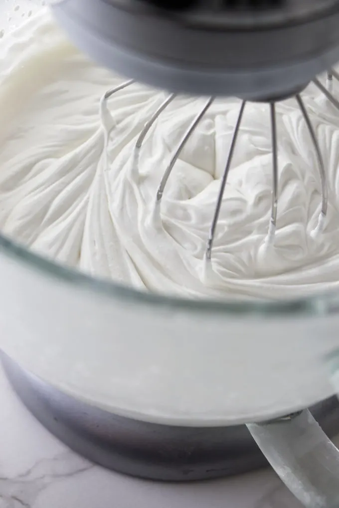 Whipping heavy cream with a whisk attachment on an electric mixer.
