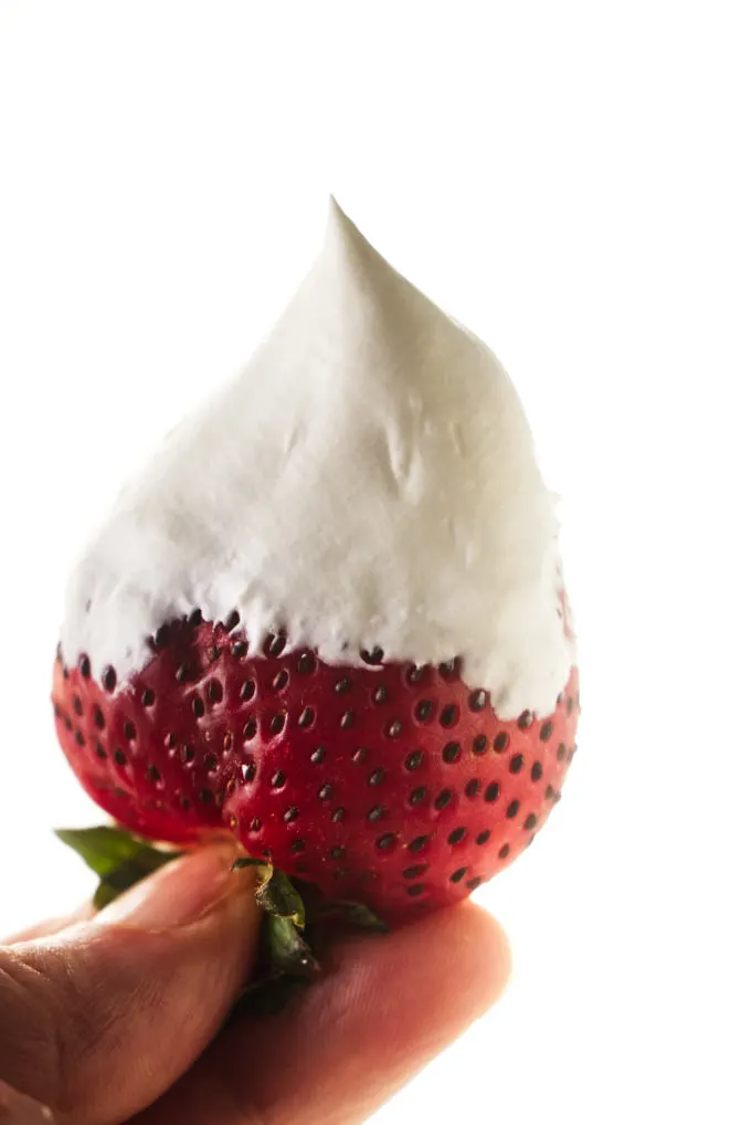 Whipped cream covering a strawberry.