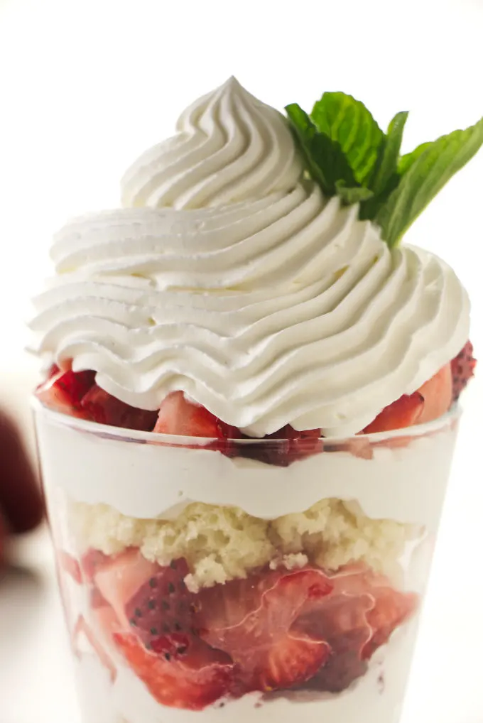 Whipped cream pipped on top of a strawberry parfait.
