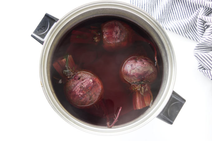 Three beets in a pot of boiling water.