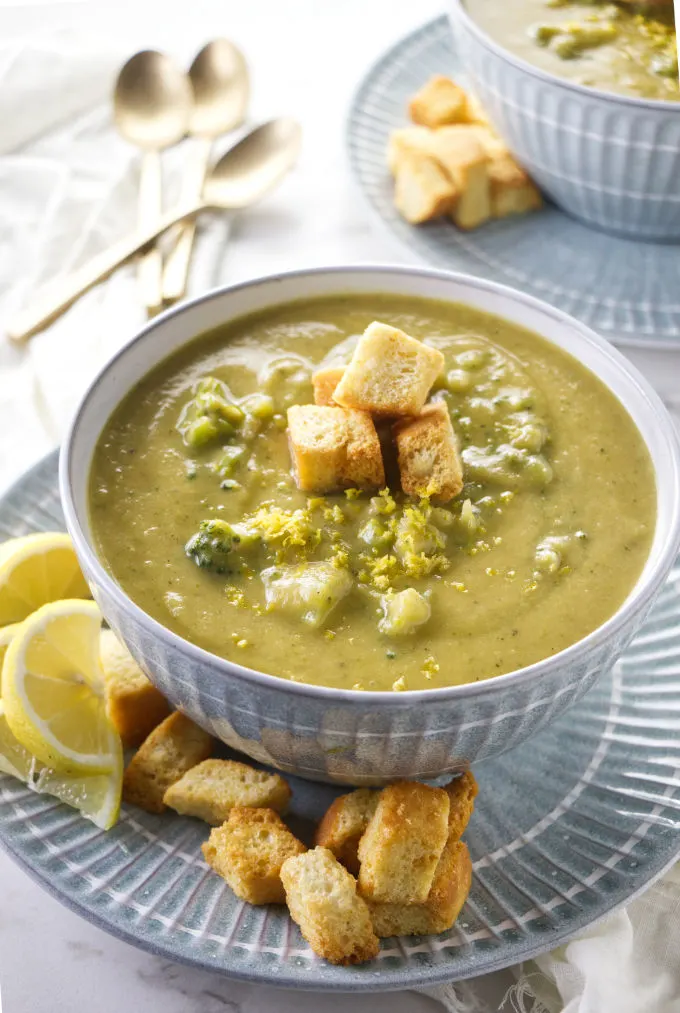 Two bowls of lemon broccoli soup with croutons.