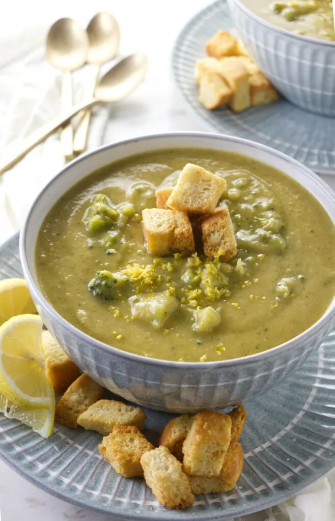 A bowl of lemon broccoli soup with spoons in the background.