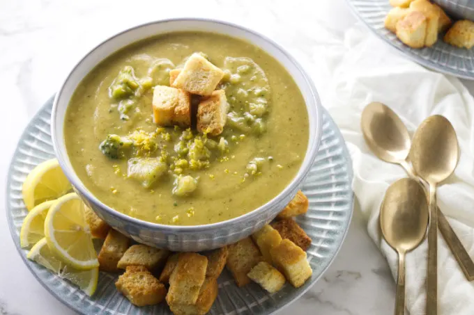 A bowl of chunky lemon broccoli soup next to three spoons.