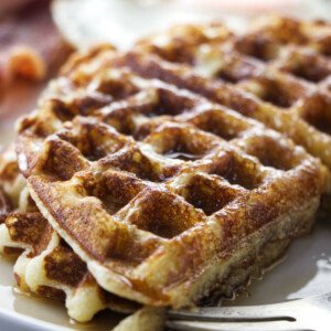 Overnight yeast waffle on a plate with a fork, egg, and bacon.