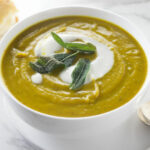 A bowl of sweet potato soup with fried sage on top.