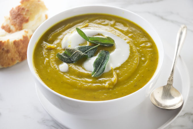 A bowl of sweet potato soup with fried sage on top.