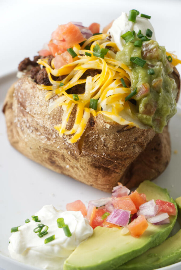 A baked potato stuffed with taco meat and taco condiments.