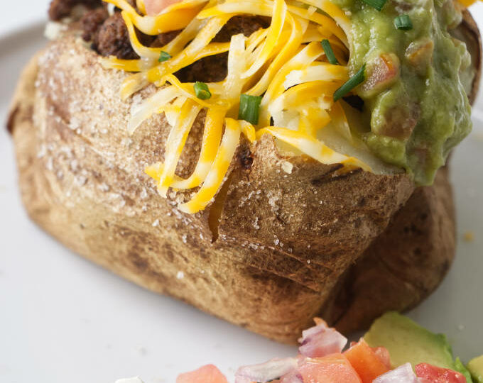 A baked potato stuffed with taco meat and taco condiments.
