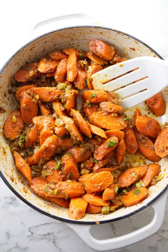 Tossing carrots with spices in a skillet.