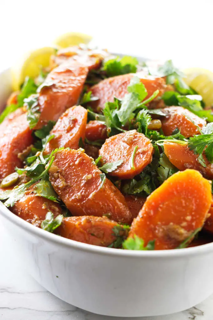 Moroccan carrot salad in a dish with lemon wedges.