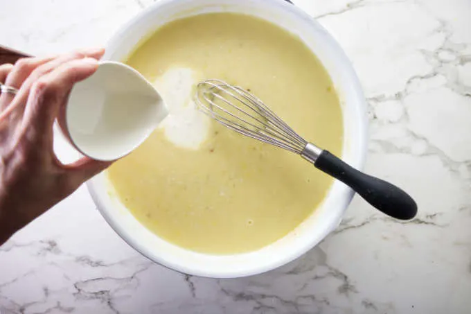 Adding cream to lemon garlic butter sauce.