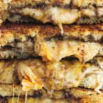 Four kimchi grilled cheese sandwiches stacked on top of each other.