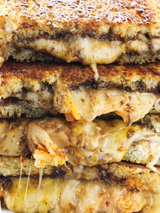 Four kimchi grilled cheese sandwiches stacked on top of each other.