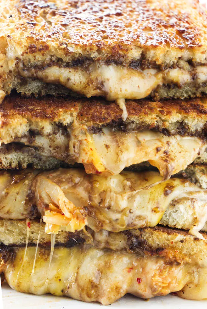 Four kimchi grilled cheese sandwiches stacked on top of each other.
