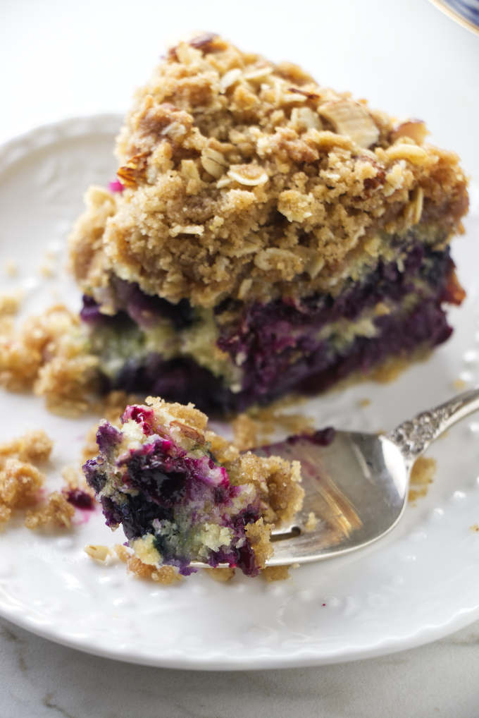 A fork scooping up a bite of blueberry buckle cake.
