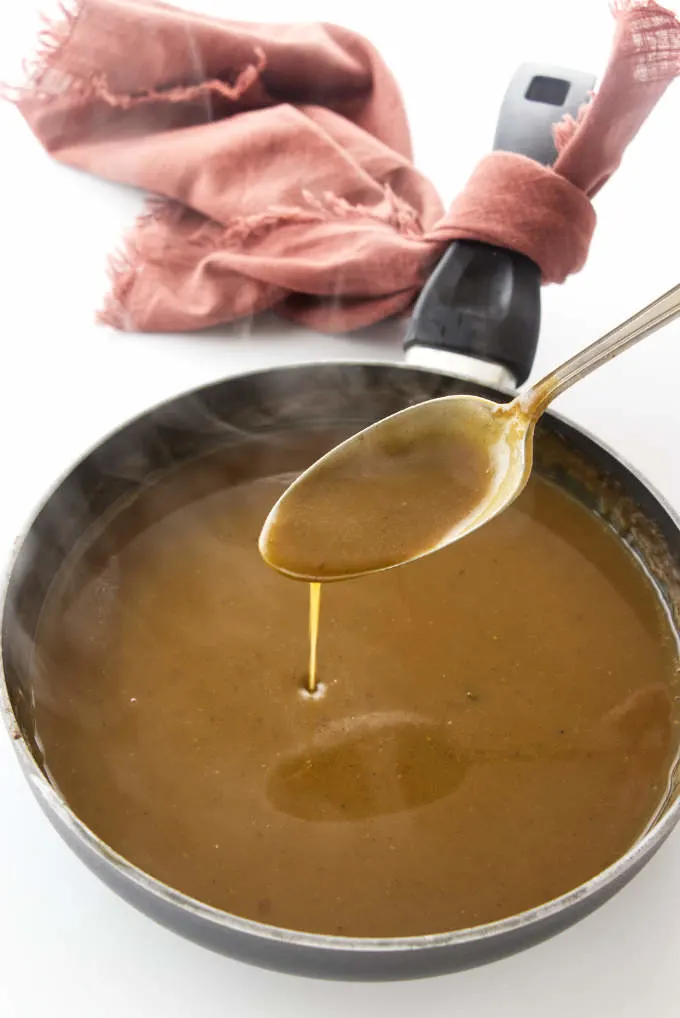 Hot steaming gravy with a spoon dripping gravy.
