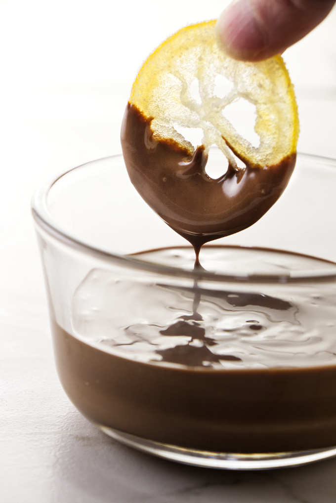 Dipping a candied lemon slice into melted chocolate.