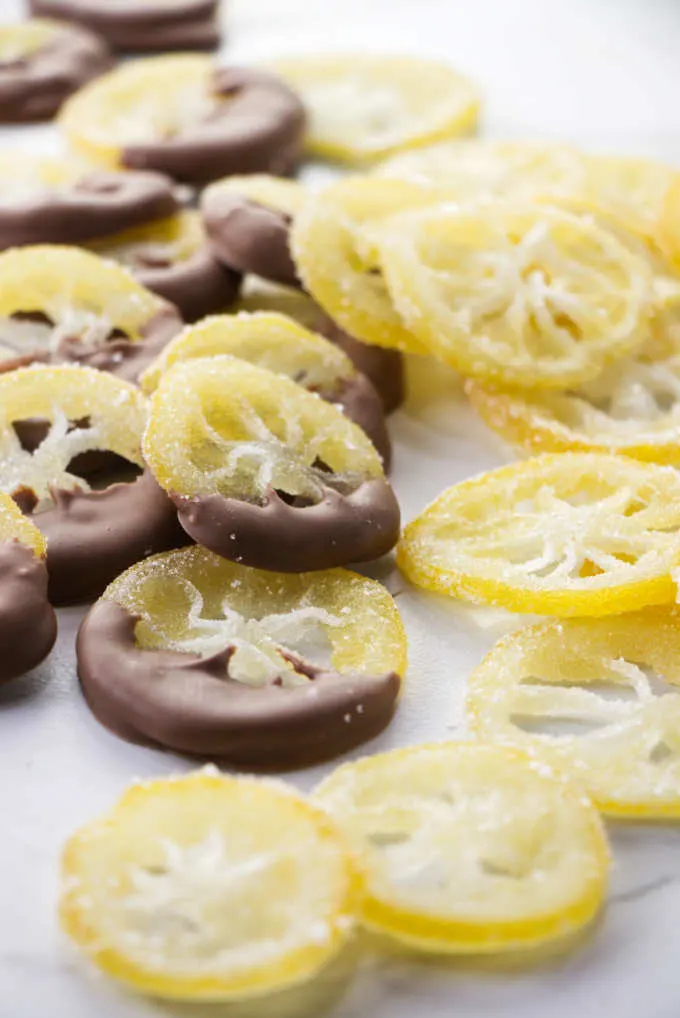 A pile of candied lemon slices coated in sugar with some of them dipped in chocolate.