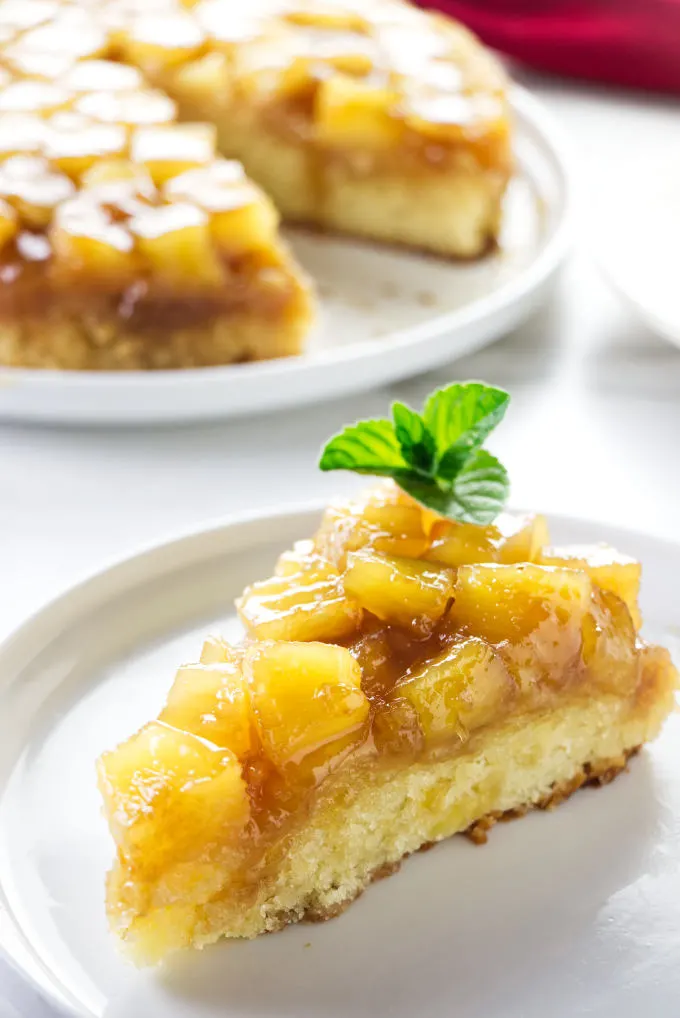 A slice of pineapple upside down cake with pineapple chunks.