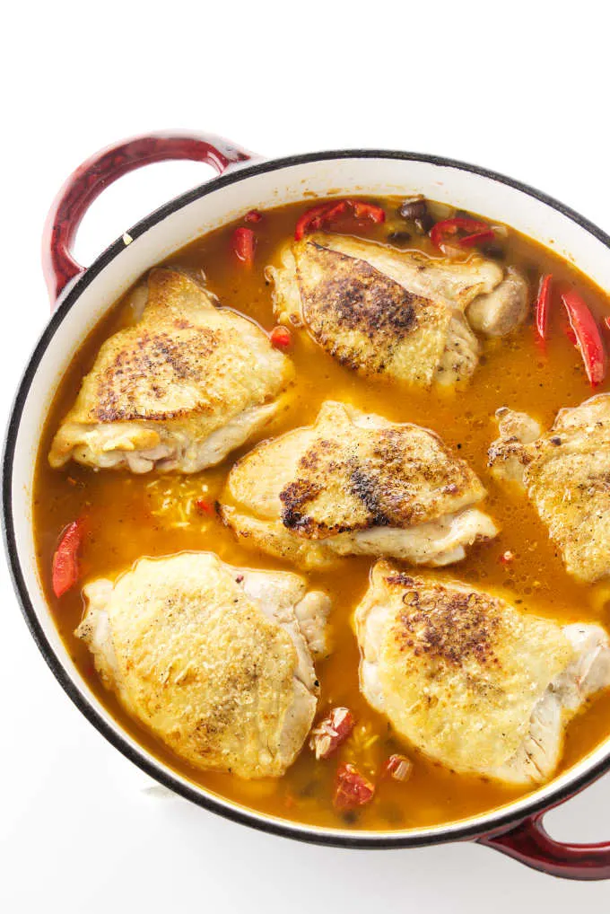 Adding chicken and broth to the skillet.
