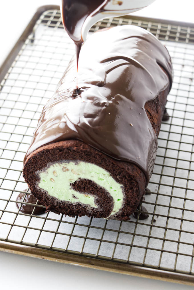 Chocolate ganache being poured on ice cream cake roll