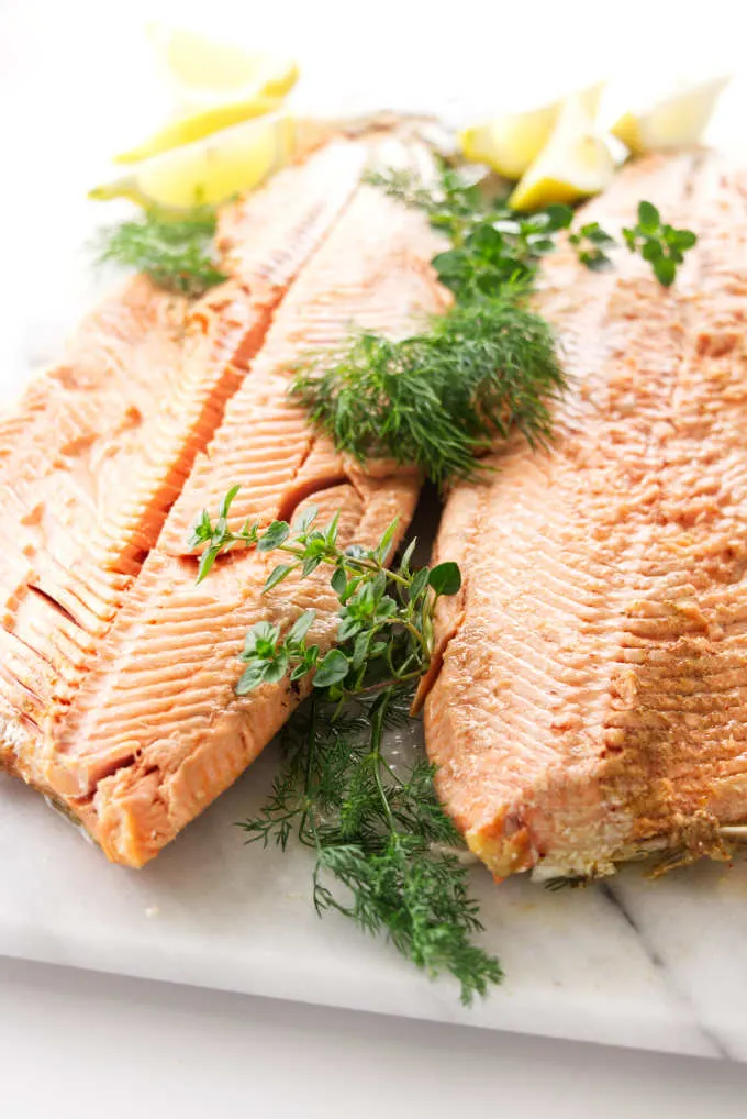 A whole baked salmon with fresh herbs.