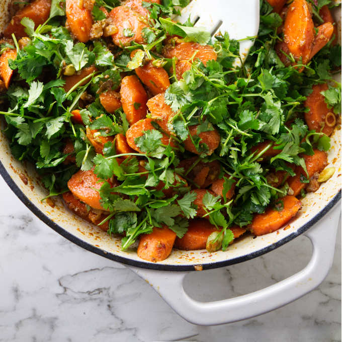 Tossing carrot salad with cilantro leaves.
