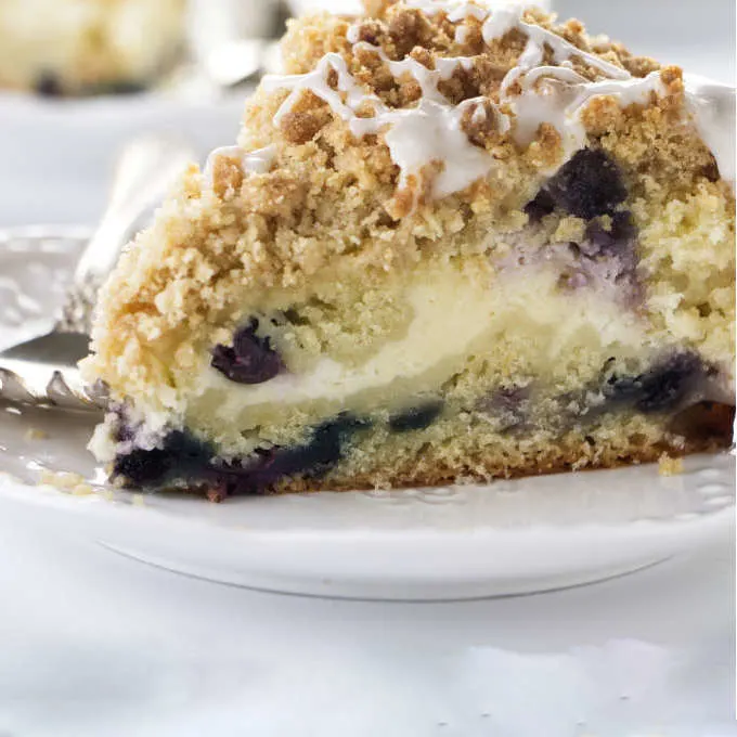 A slice of blueberry coffee cake filled with cheesecake.