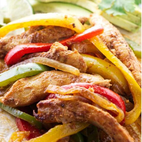 A close up of chicken fajitas with red, green, and yellow bell peppers.