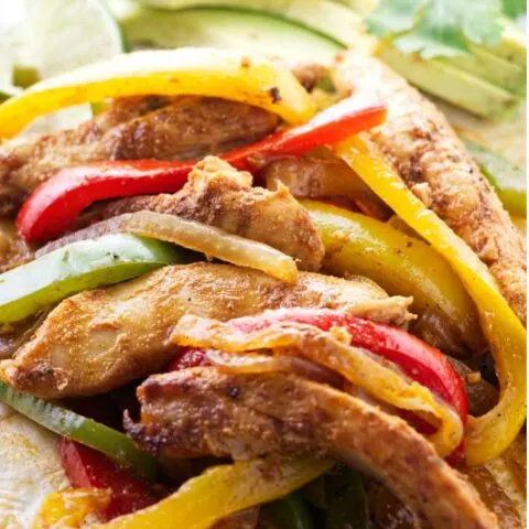 A close up of chicken fajitas with red, green, and yellow bell peppers.
