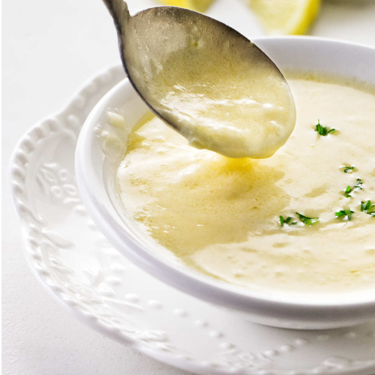 A spoon dipping into a dish of lemon garlic butter sauce.
