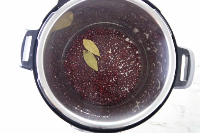 Dry adzuki beans in an instant pot with water and bay leaves.