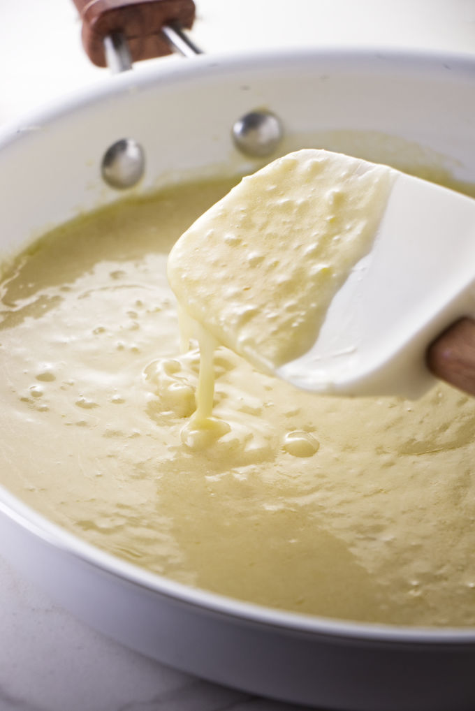 A spatula stirring lemon garlic butter sauce in a pan.