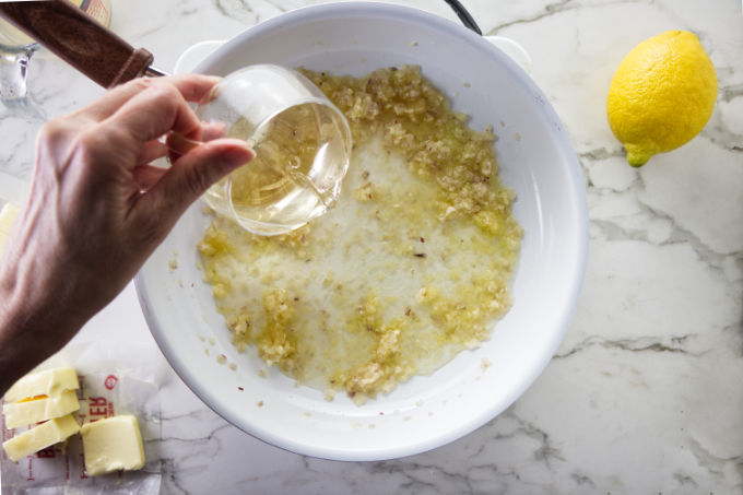 Pouring wine into a pan to show how to make lemon garlic butter sauce.