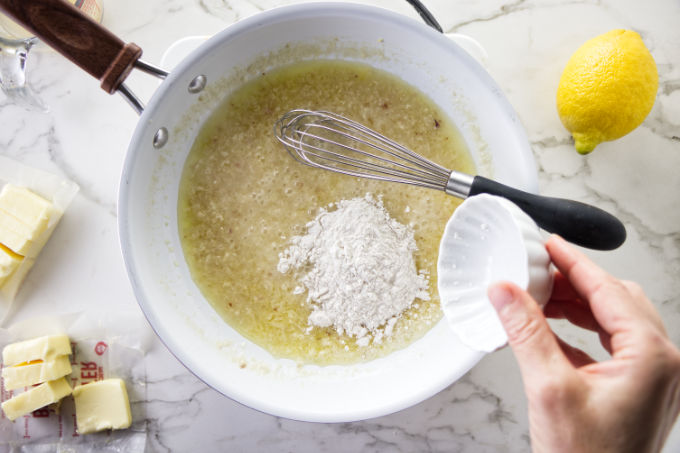 Adding flour to a pan to show how to make lemon garlic butter sauce.