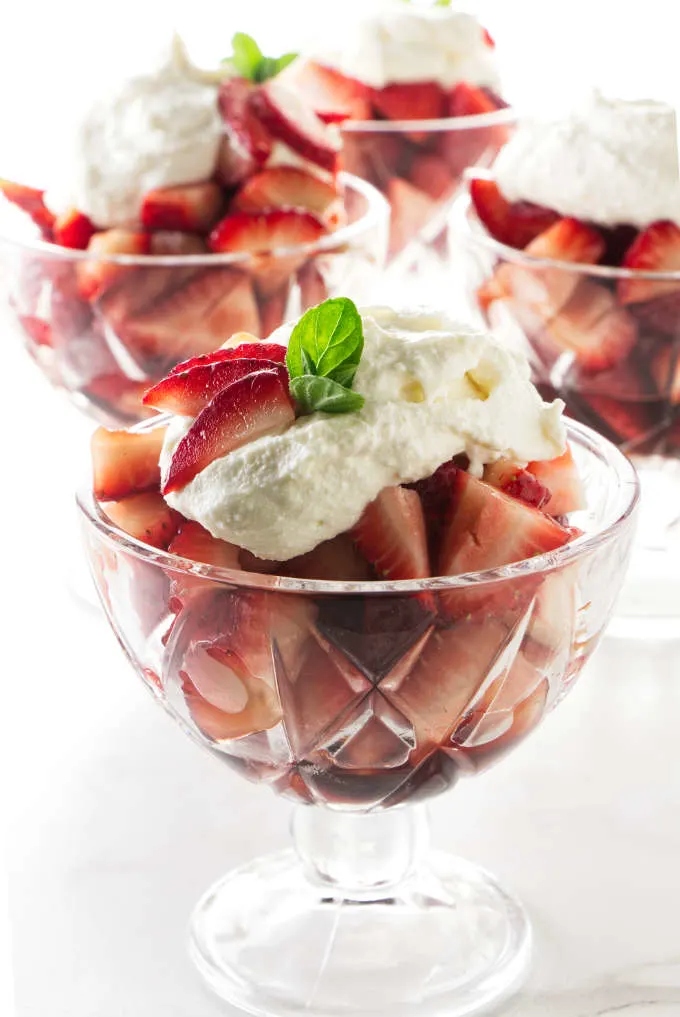 Four dessert glasses filled with marsala strawberries and topped with sweetened ricotta.