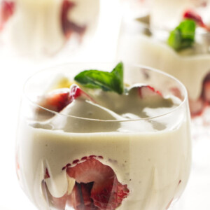 Four wine glasses filled with zabaglione and strawberries.