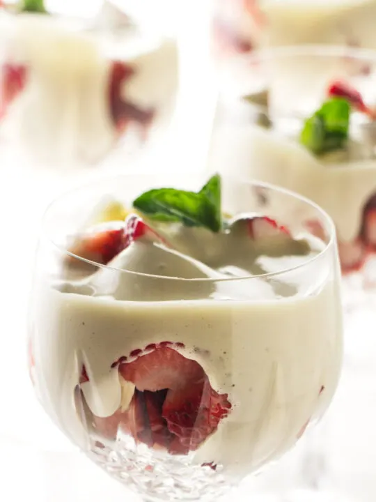 Four wine glasses filled with zabaglione and strawberries.