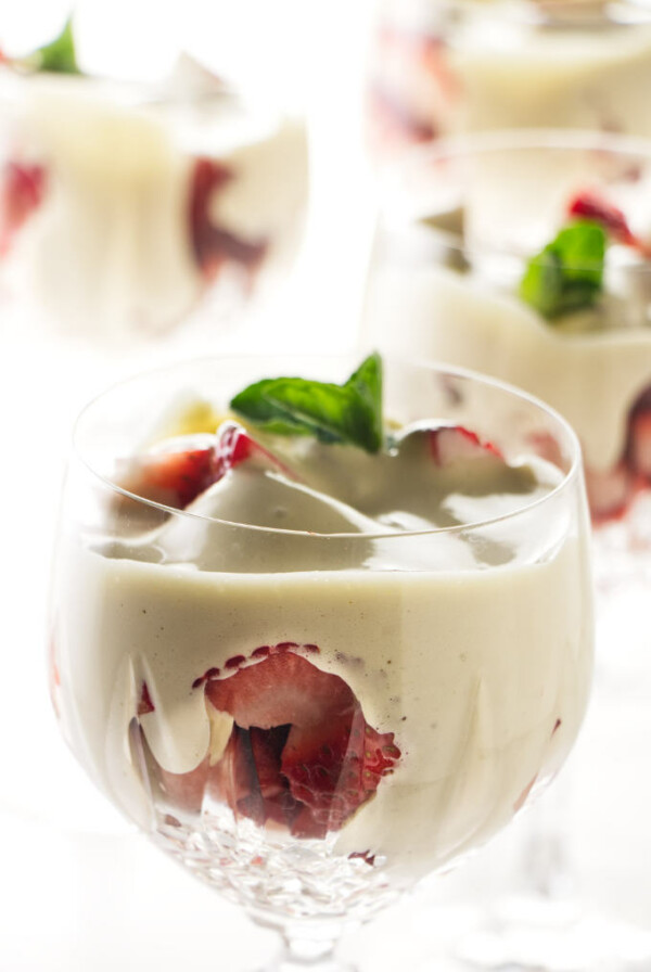 Four wine glasses filled with zabaglione and strawberries.