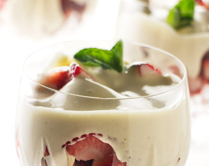 Four wine glasses filled with zabaglione and strawberries.