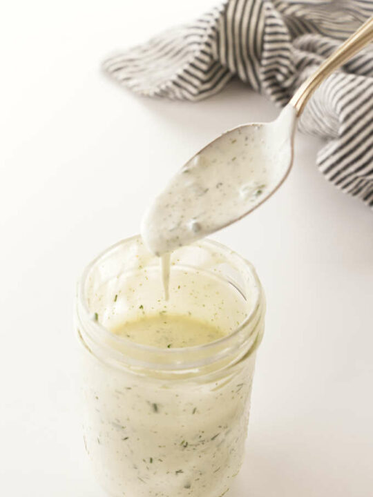a mason jar of buttermilk ranch salad dressing and a spoon