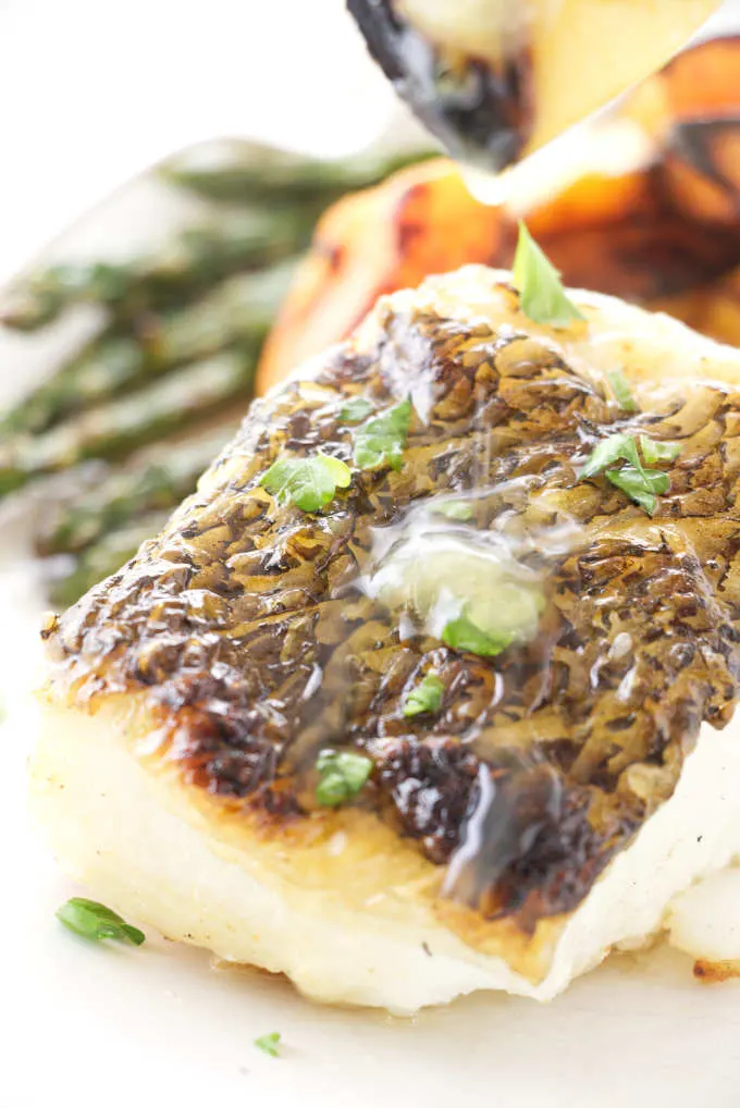 Close up view of grilled lemon being squeezed on Chilean Sea Bass