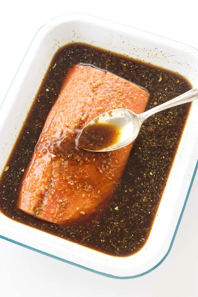 A salmon fillet in a dish with bourbon marinade.