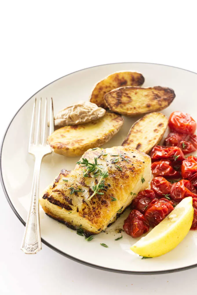 Overhead view of a butterr-thyme basted sea bass filet, roasted fingerling potatoes and grape tomatoes