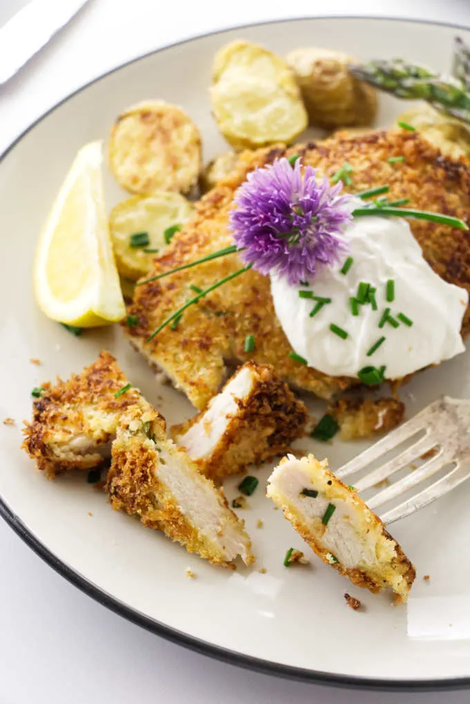 A serving of crispy chicken with sour cream and chives and a bite on a fork