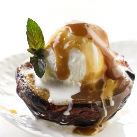 A grilled peach with ice cream and caramel sauce on top.