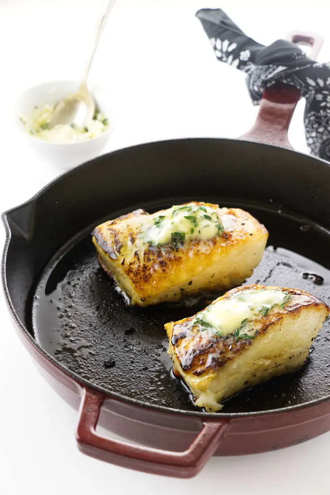 Thyme and butter basted Chilean Sea Bass filets in a skillet