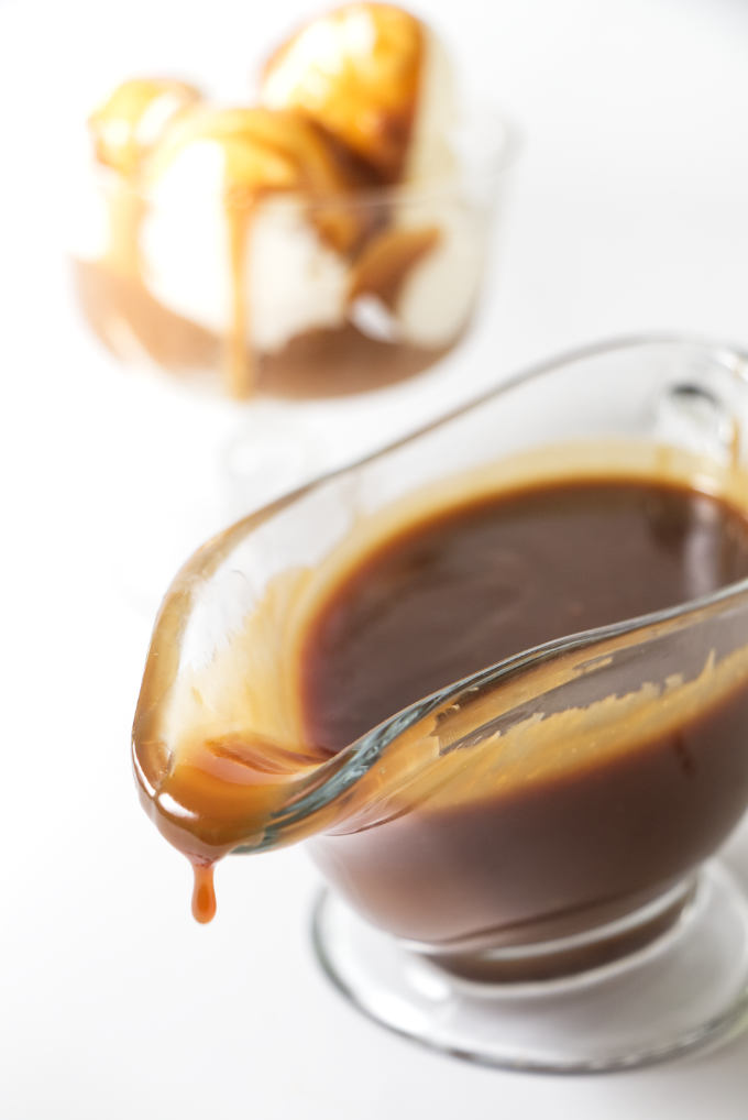 Butterscotch sauce in a dish with ice cream in the background.